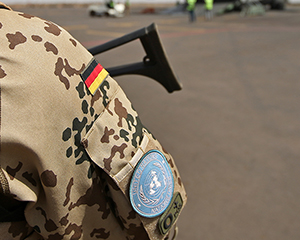 Bild zeigt einen Bundeswehr-Soldaten in Mali, auf dessen Ärmel die deutsche Flagge und das Abzeichen der UN zu sehen sind