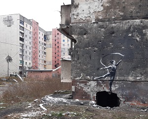 Ein tanzendes Mädchen, gemalt von Banksy auf ein zerstörtes Gebäude in Irpin