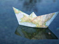 Foto eines Papierschiffs aus einer Weltkarte auf Wasser