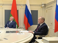 Putin und Lukaschenko sitzen an einem Tisch. Hinter ihnen sind die Flaggen Russlands und Belarus aufgestellt.