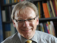 Profile picture of smiling Prof. Dr. Thilo Marauhn in front of a wall of books.