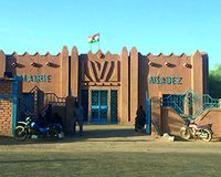 Rathaus von Agadez mit Flagge von Niger und Schriftzug "Mairie Agadez". Vor dem Gebäude sind Motorräder geparkt.